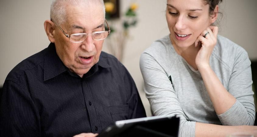 Contextual inquiry: An older gentleman uses a tablet while a female researcher observes.