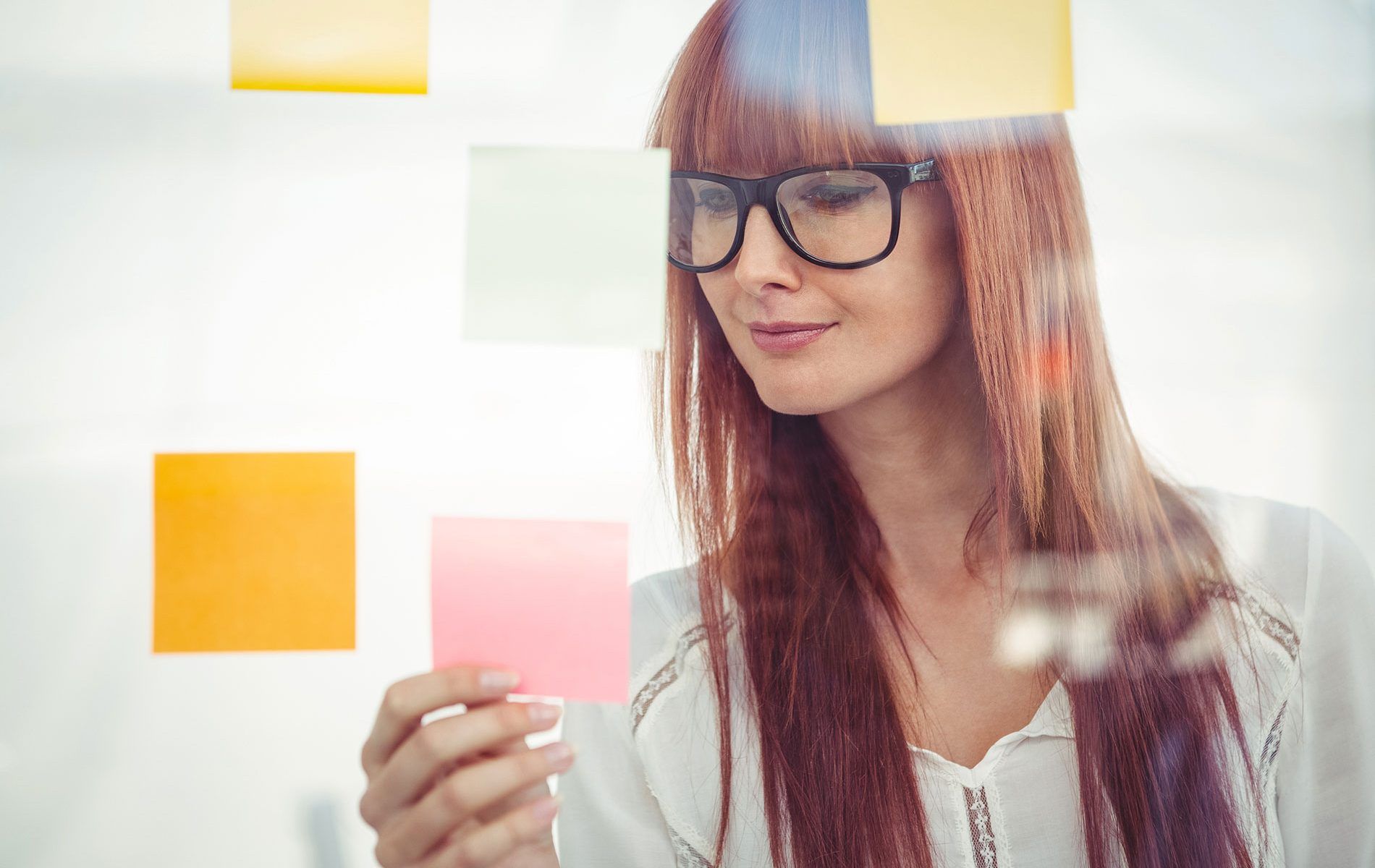 Eine Frau gruppiert ihre Inhalte mithilfe von bunten Post-Its.