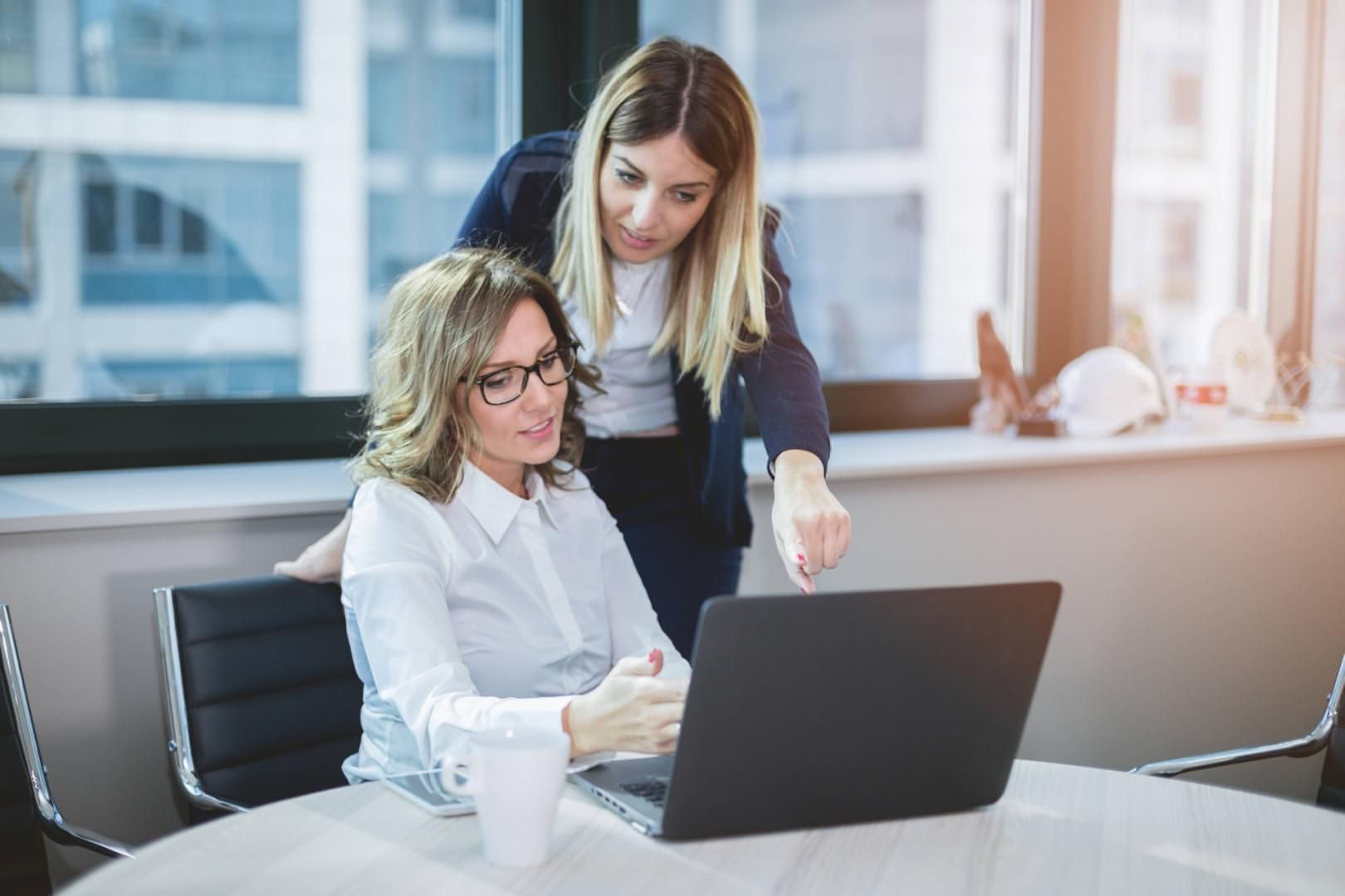 contextual inquiry: one woman explains something to another on a laptop