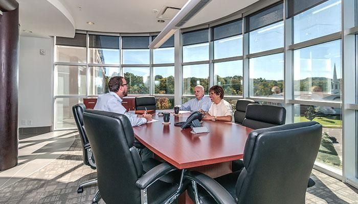 contextual inquiry: three people sit at a table in a large conference room