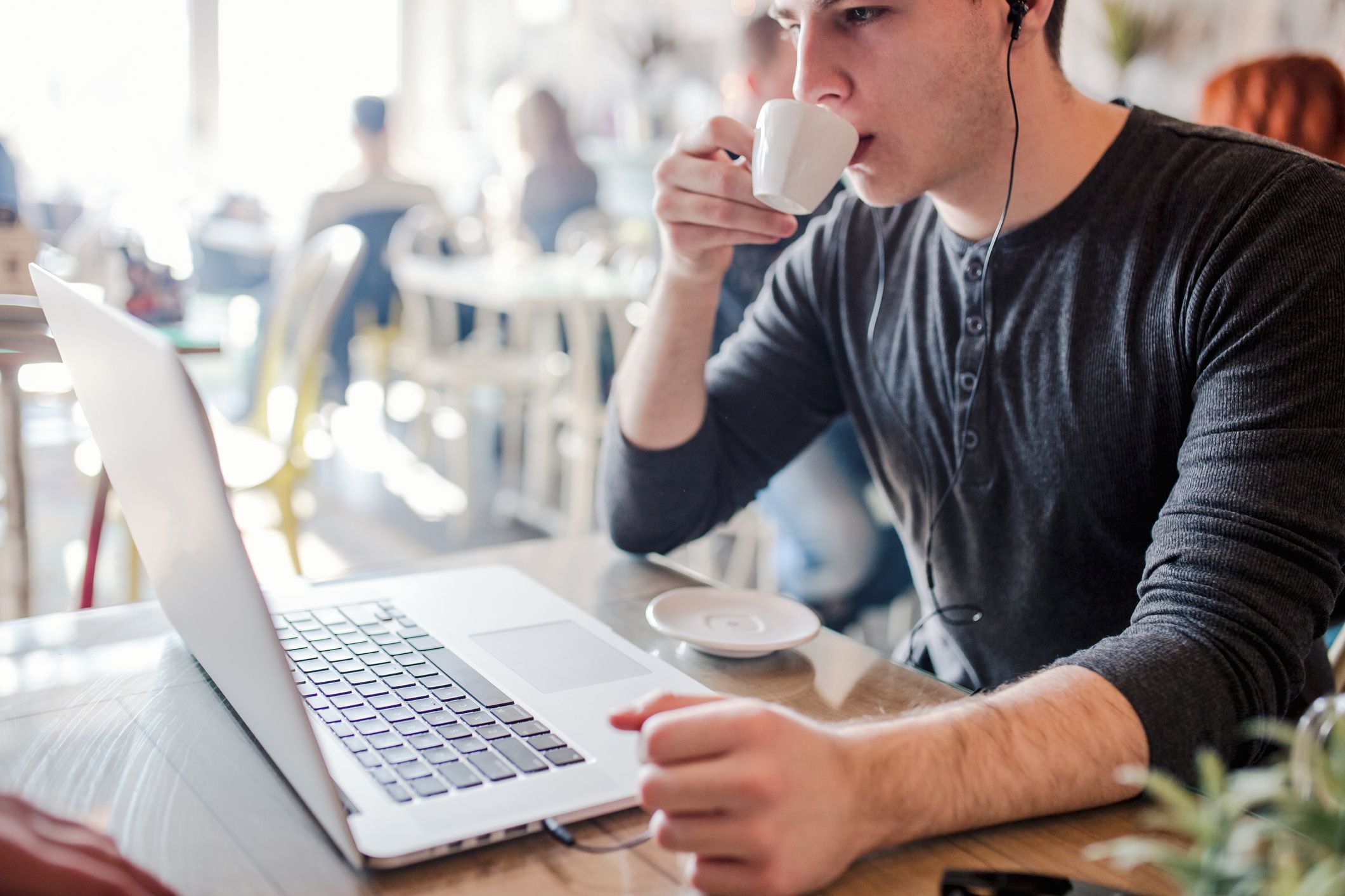 Ein Mann mit Kopfhörern trinkt eine Tasse Kaffee und vertieft sich in seine Human Data Analytics.