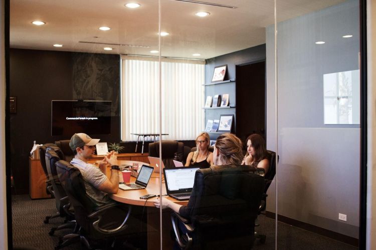 3 women and 1 man sitting in a meeting room doing a UX workshop.